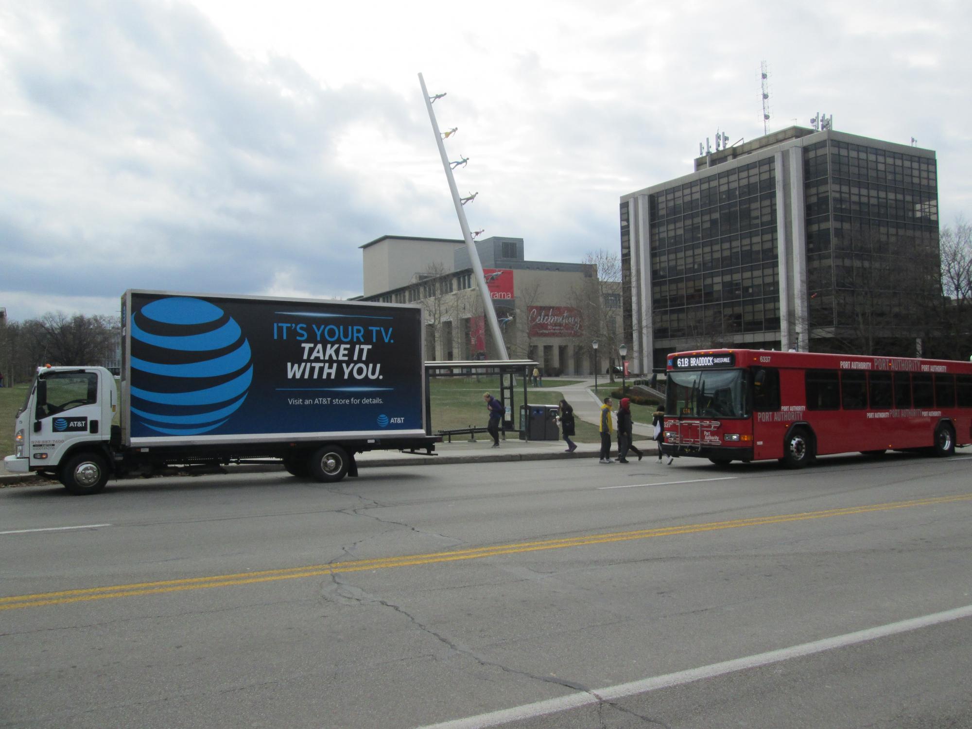 Billboard truck stopped in front of the Walking to the Sky sculpture.