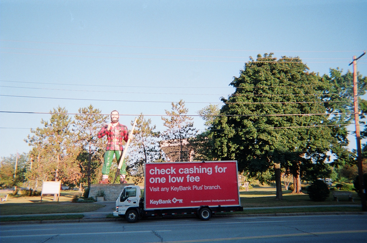 Billboard truck stopped in front of lumberjack statue in Bangor ME