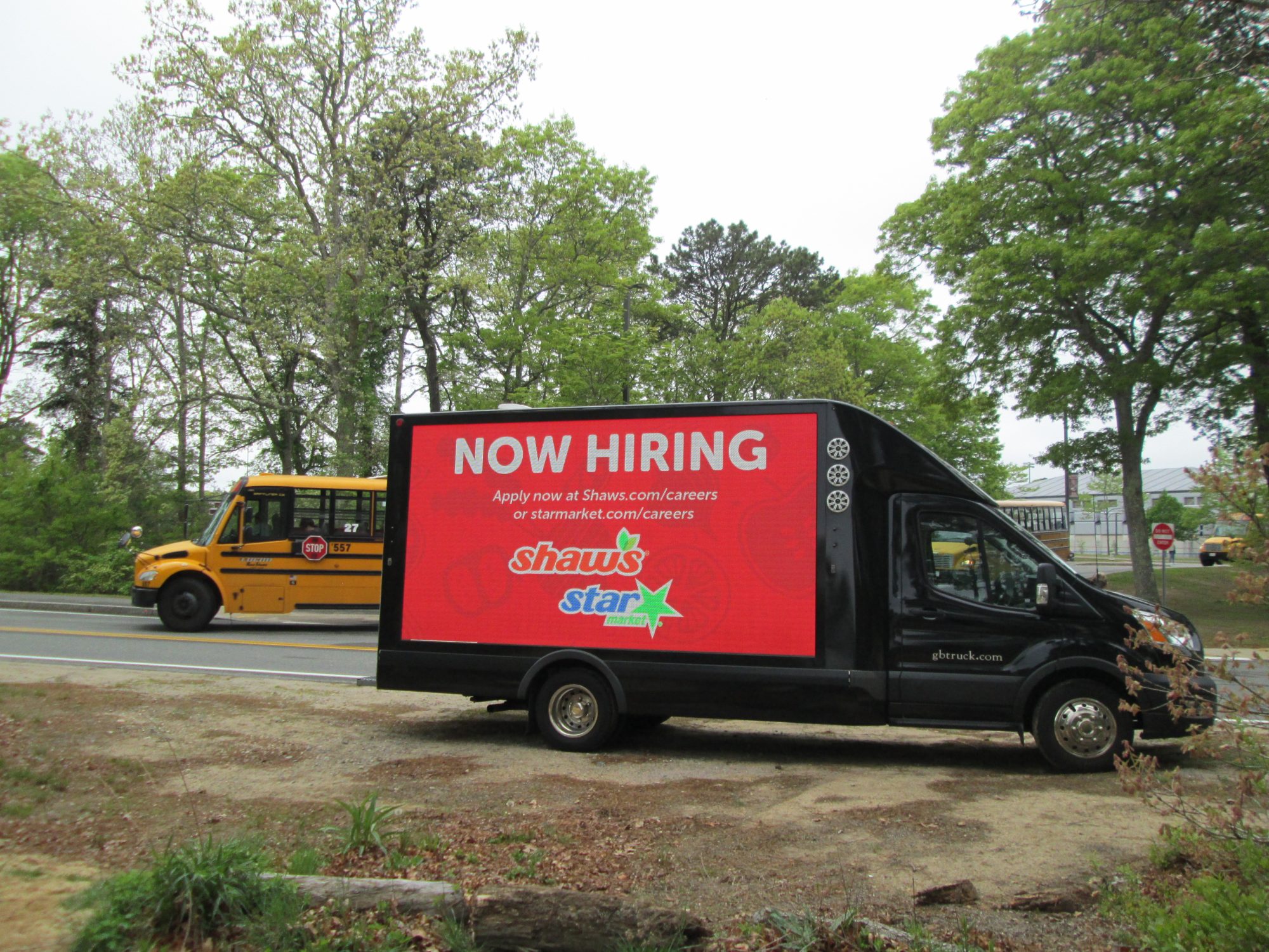 LED mobile billboard truck with a Now Hiring ad stopped at Falmouth High School on Cape Cod, during afternoon dismissal,