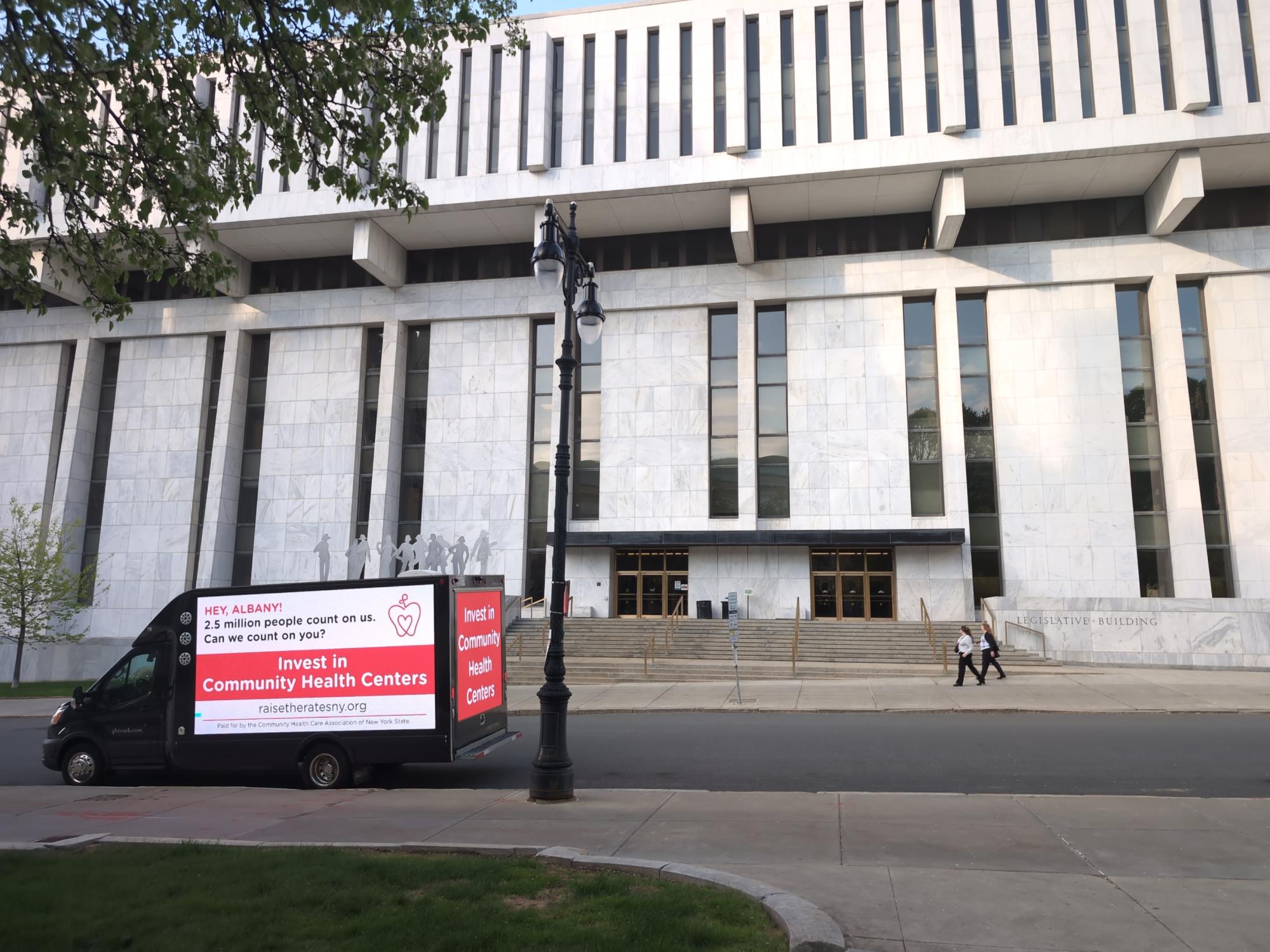 Digital LED mobile billboard truck with a community health center message stopped in front of the Legislative Building in Albany NY