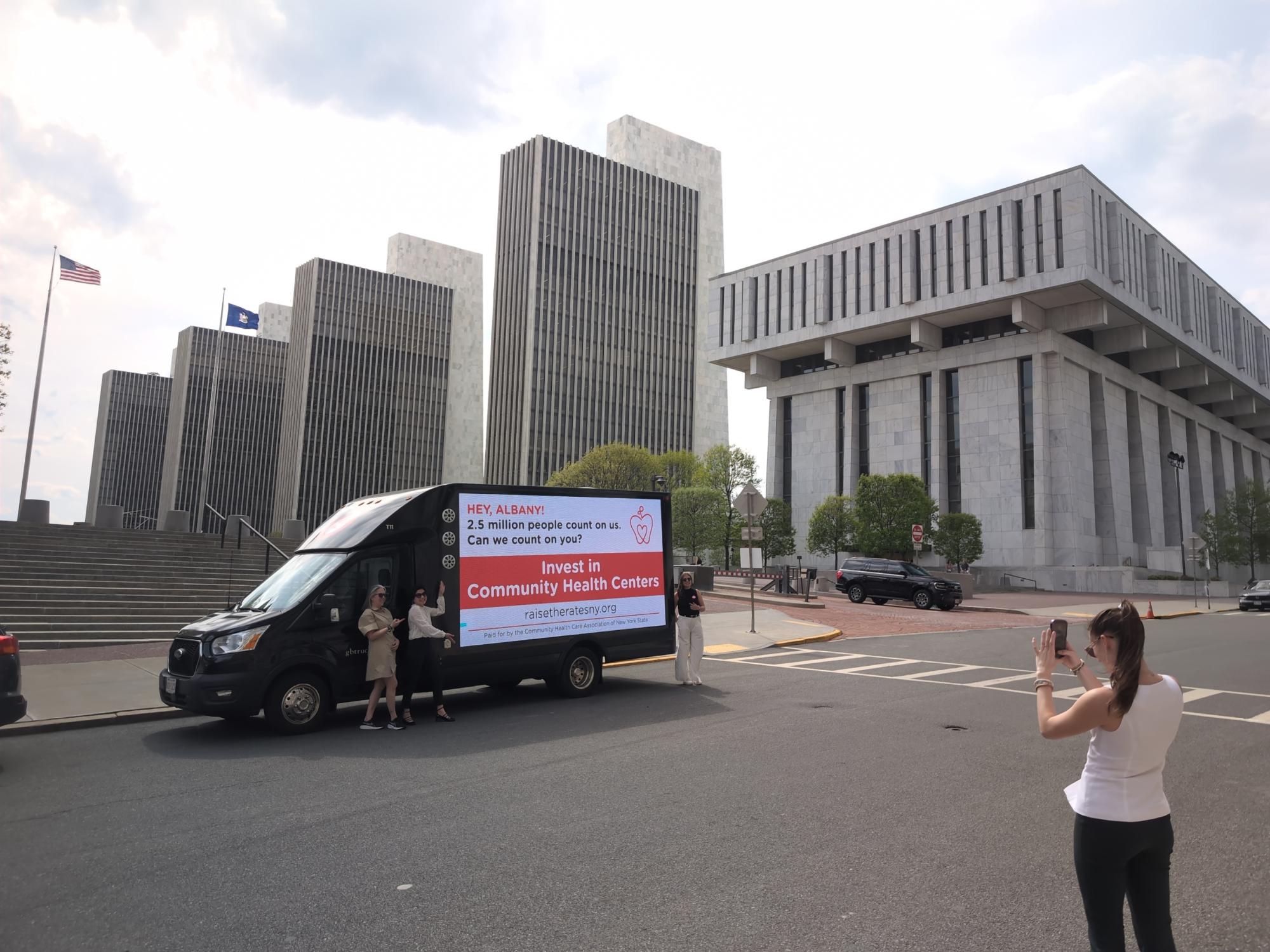 Ad agency representatives posing with a client's digital mobile billboard truck message in Albany NY
